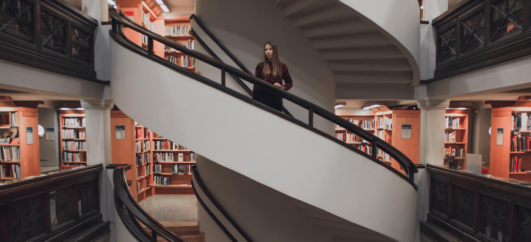 Woman standing on stairs in a library in Helsinki.