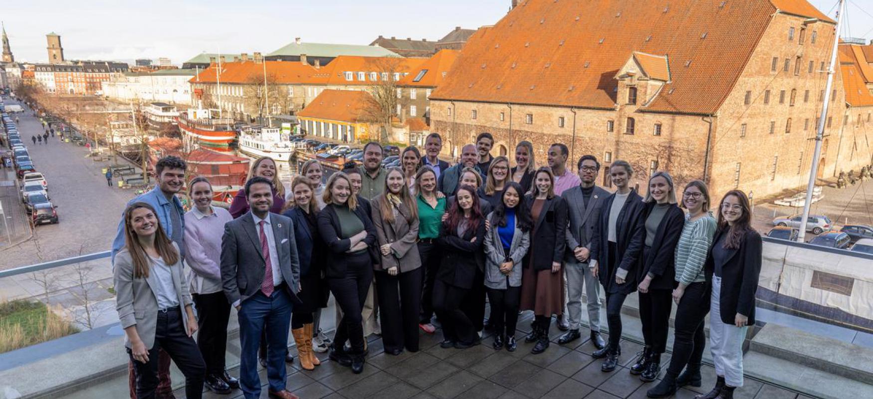 Attendees at the Nordic Circular Summit from Nordic Innovation, Nordic Circular Hotspot, Regeneration 2030 and DTU Skylab standing together smiling at the camera with a sunny copenhagen in the background. 