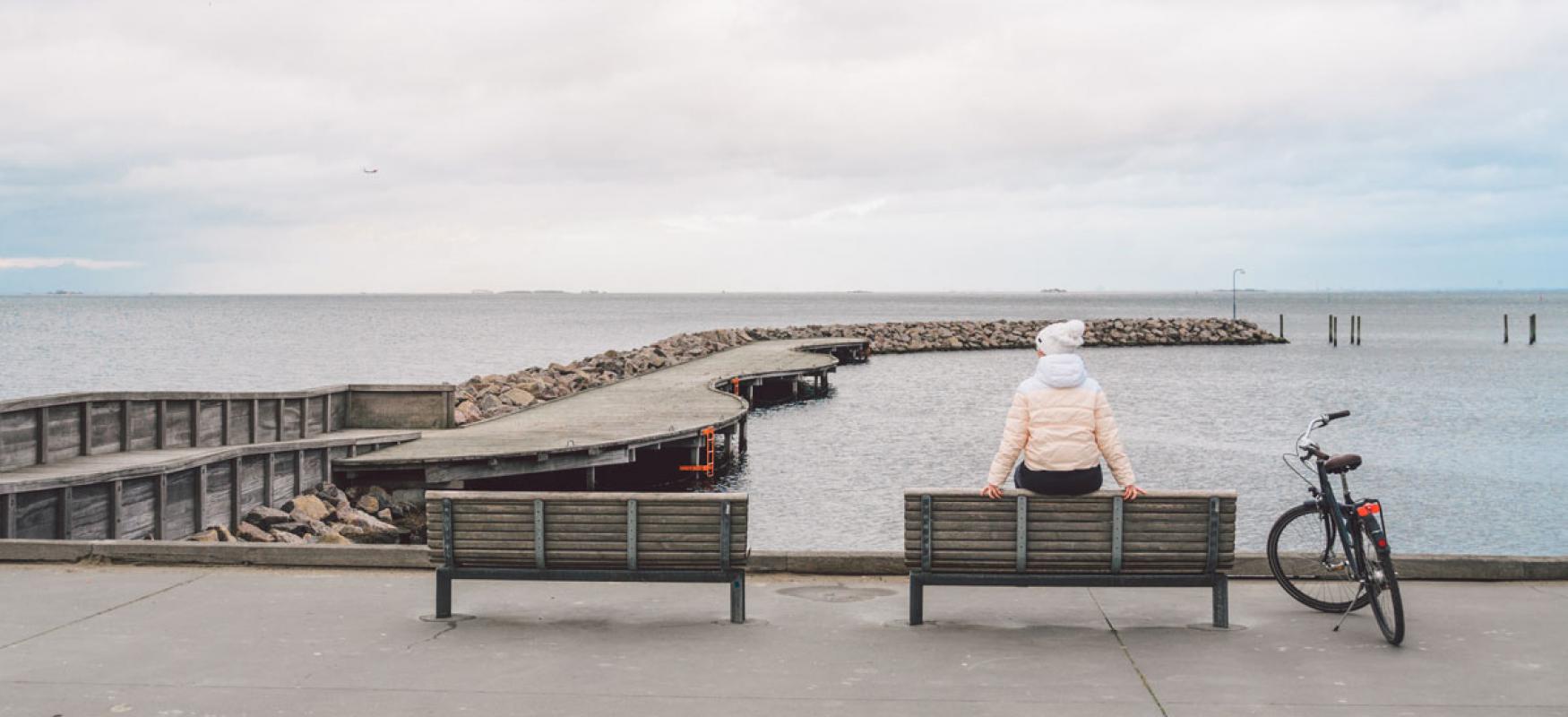 Woman on bench by the sea in Copenhagen.