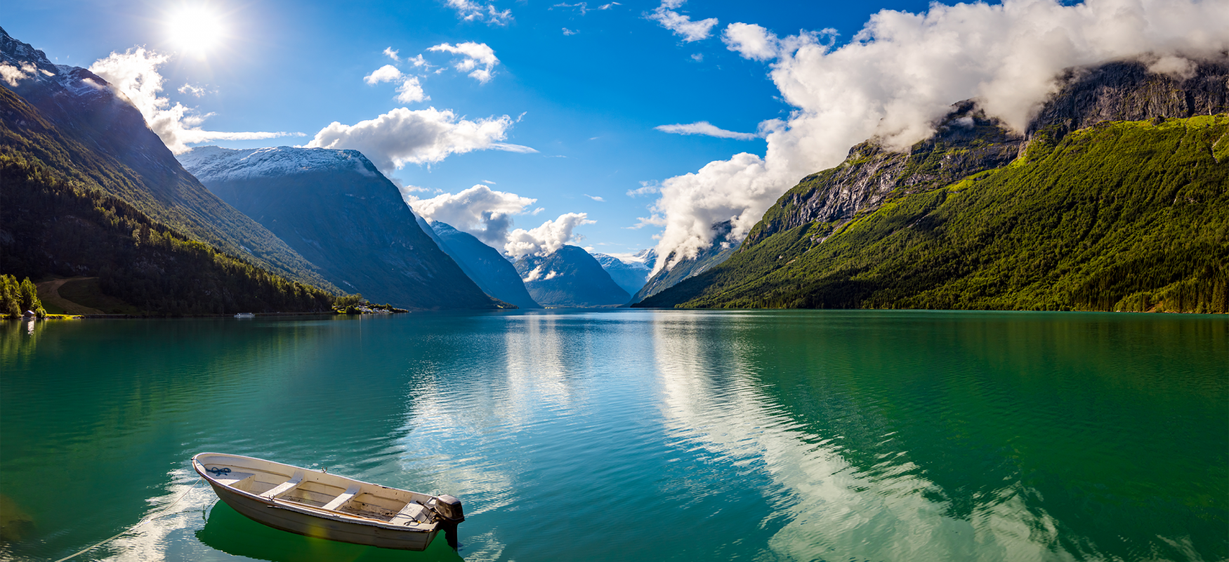 Small boat on the water in between mountains in Norway.