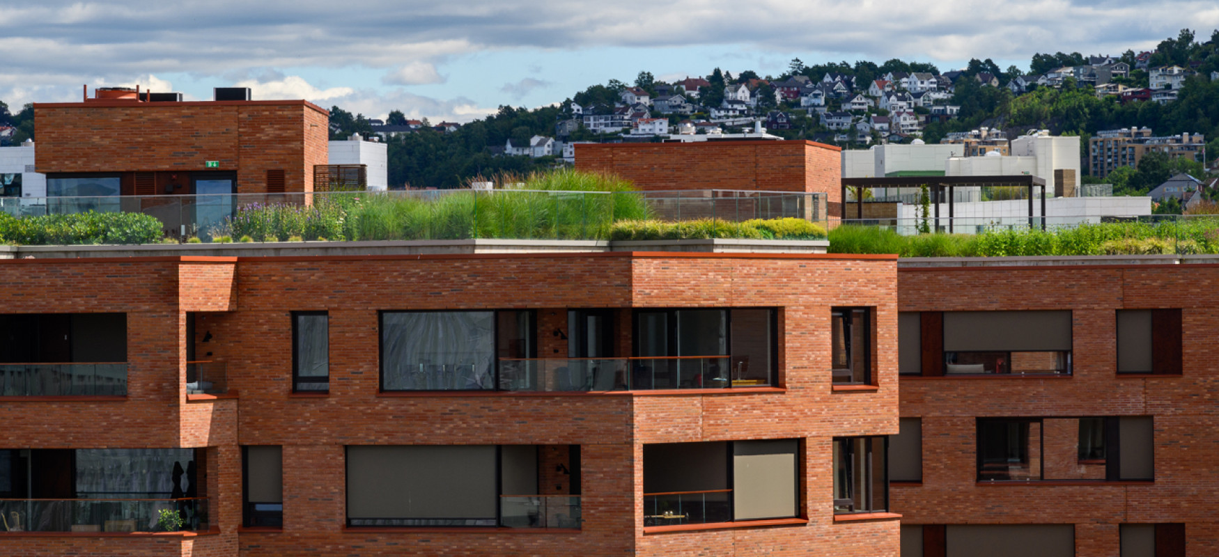 Fasade of brick layed higrise buildings in Oslo with green bushes on top