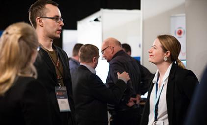 People discussing infront of an exhibition stand.