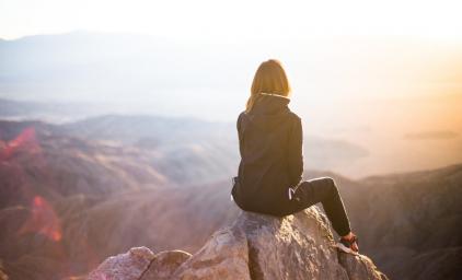 Woman sitting on top of a mountain looking at the landscape 