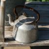 kettle standing outside on wooden shelf.