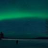 Tourist standing at night looking up at the northern lights.
