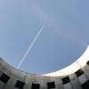  photography taken stright upward of brown concrete building under blue sky and a plane. Photo by Ben Krb on Unsplash
